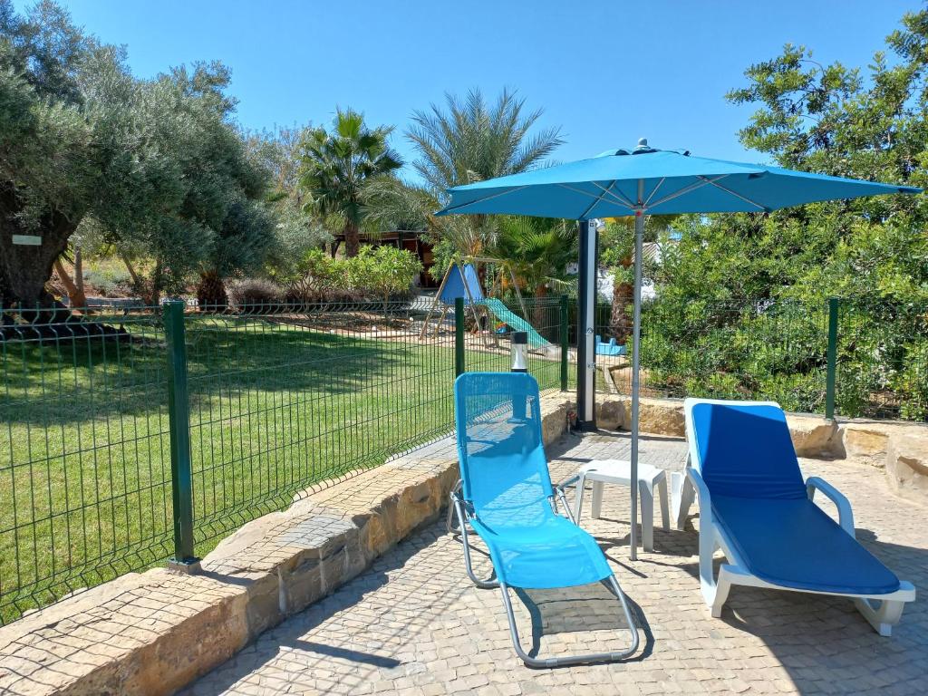 2 sillas azules y una sombrilla en el patio en Monte da Caldeirinha, en Luz de Tavira