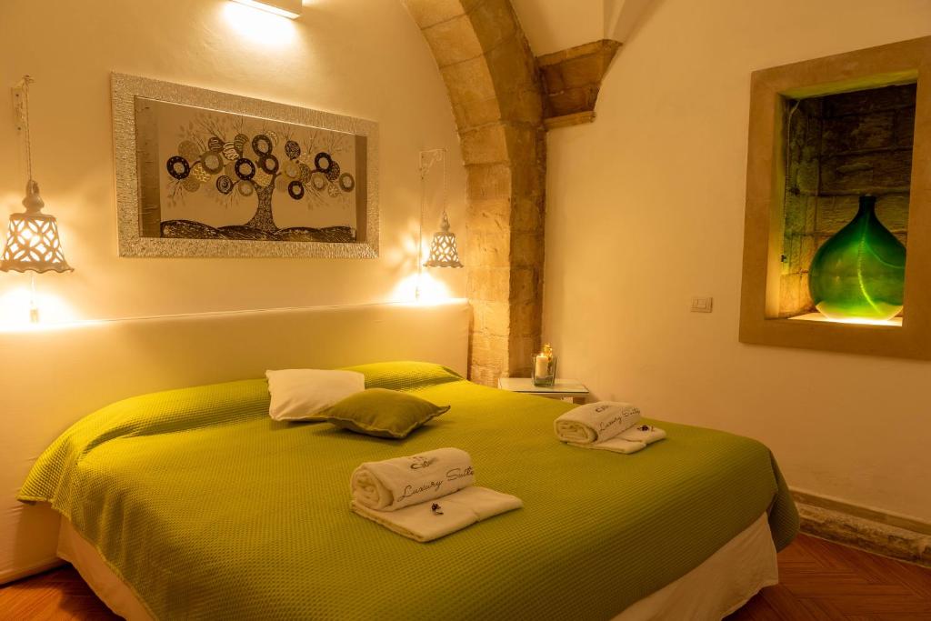 una camera da letto con un letto verde e asciugamani di Cadelli Luxury Suite & Apartments a Lecce
