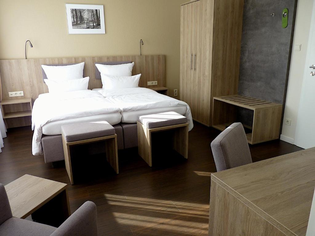 a bedroom with a large bed with two tables and chairs at Hotel Jellentrup in Münster