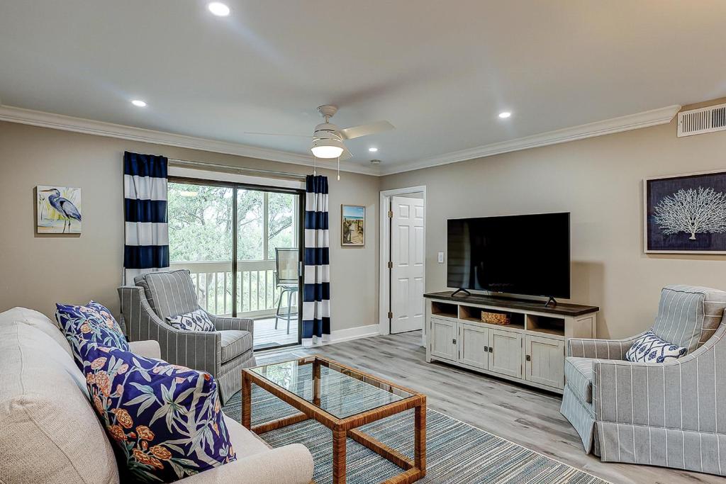a living room with a couch and a flat screen tv at Bend in the Road 2003 in Seabrook Island