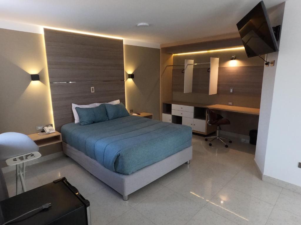a bedroom with a bed and a desk and a television at Hotel Tierra del Sol Moquegua in Moquegua