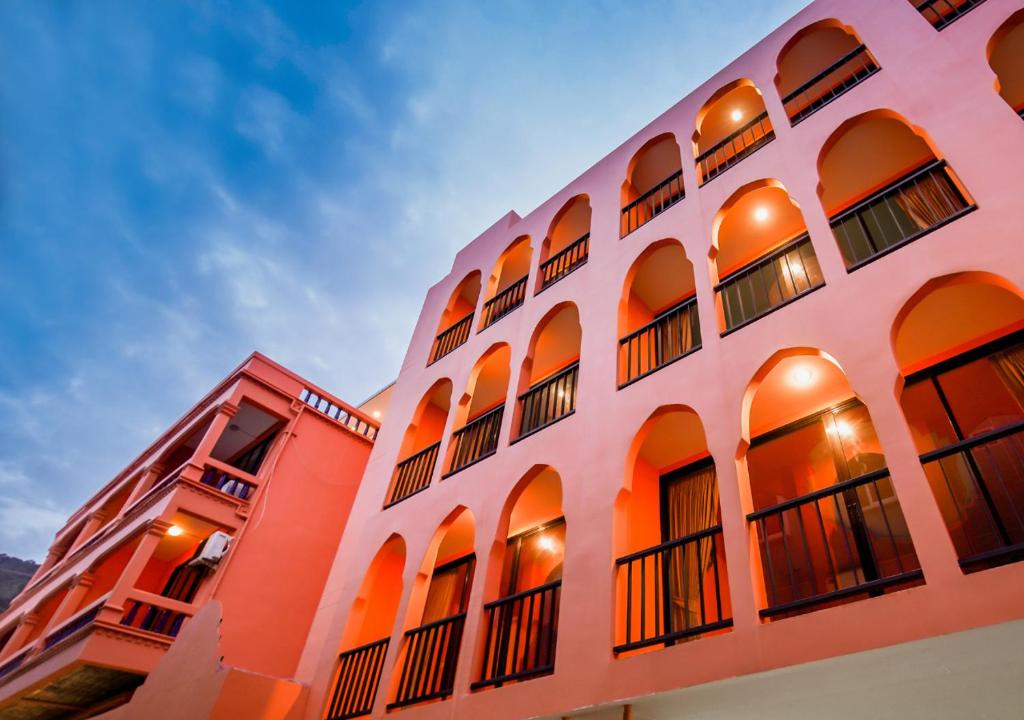 a building with orange and white walls and windows at Khaleej Mass Hotel Patong in Patong Beach