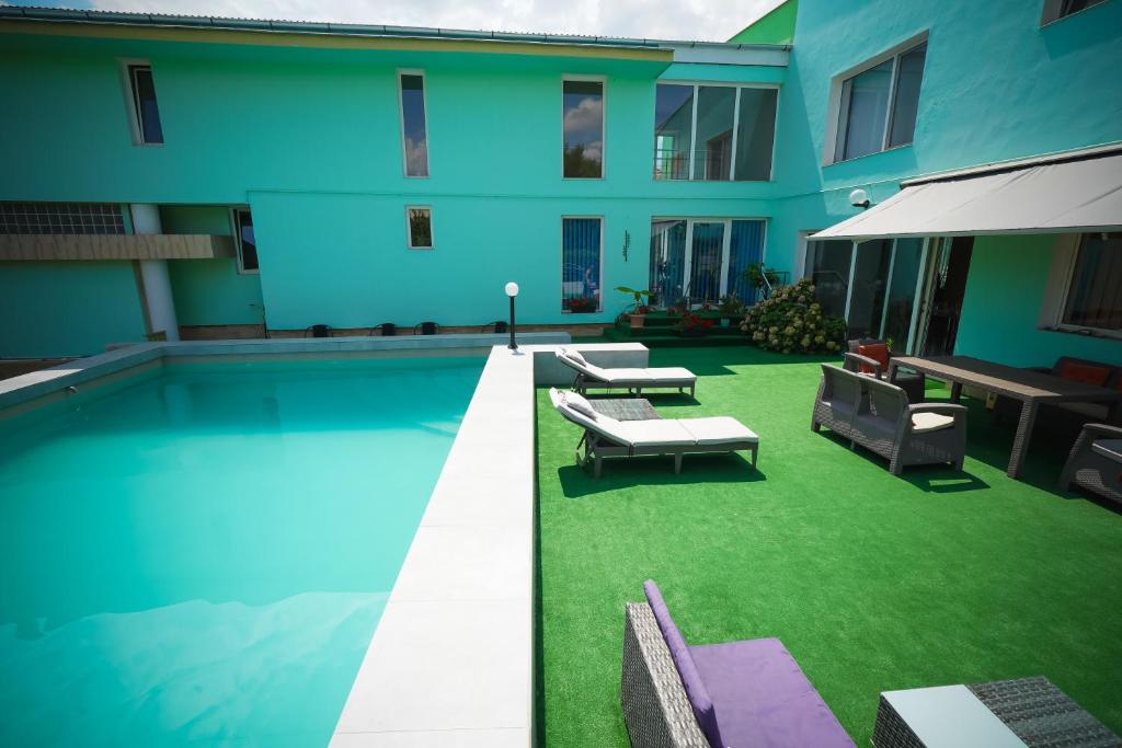 a swimming pool with green grass next to a building at Pensiunea Dolce in Timişoara