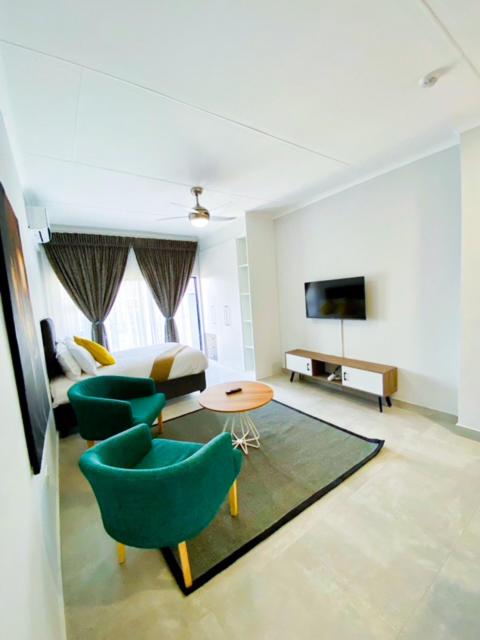 uma sala de estar com um sofá e cadeiras e uma televisão em 303 Luxury Suite em Gaborone