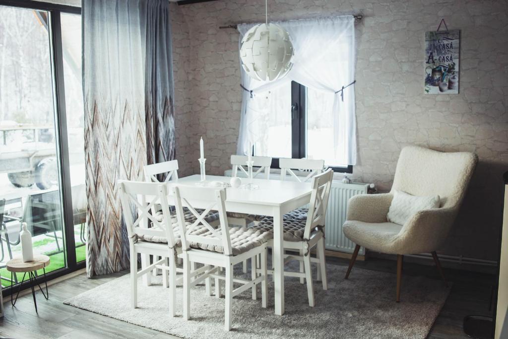 ein Esszimmer mit einem weißen Tisch und Stühlen in der Unterkunft Acasă Straja - Casa Nordică in Lupeni