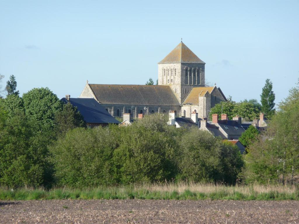 un bâtiment avec une tour arborée au loin dans l'établissement Du marais à la mer, à Lessay