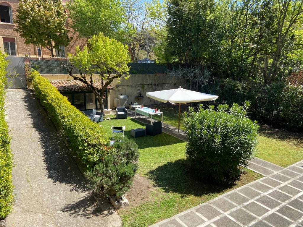 a garden with an umbrella and chairs and bushes at Vagabunda Sea & Garden in Pesaro