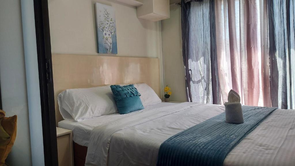 a bedroom with a bed with blue pillows and a window at 1bedroom one oasis condo fullyfurnished in Davao City