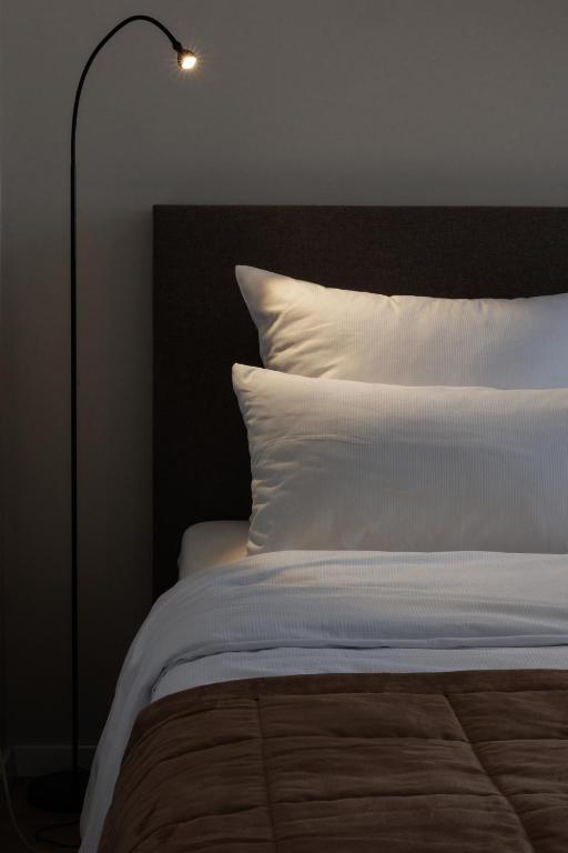 a bedroom with a bed with white sheets and a lamp at Hotel Jellentrup in Münster