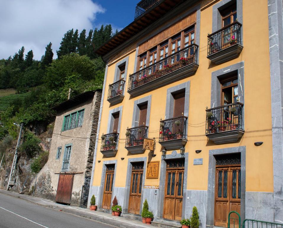 um edifício amarelo com portas de madeira e varandas numa rua em Apartamentos Rurales Las Mestas em Puenteciella