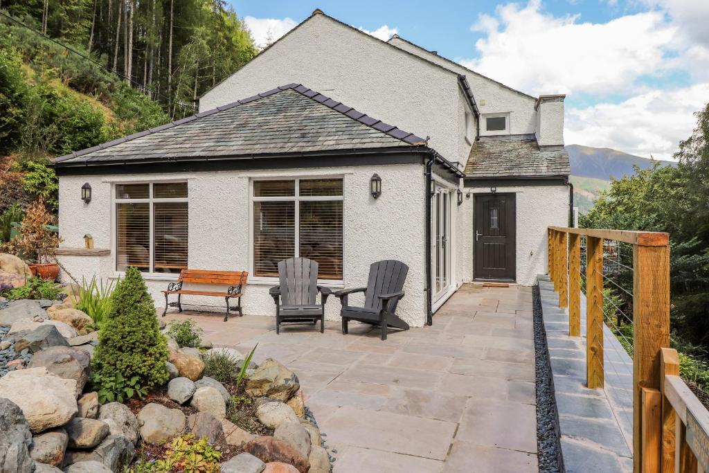 a house with a patio with two chairs and a table at Ladstock Cottage in Keswick