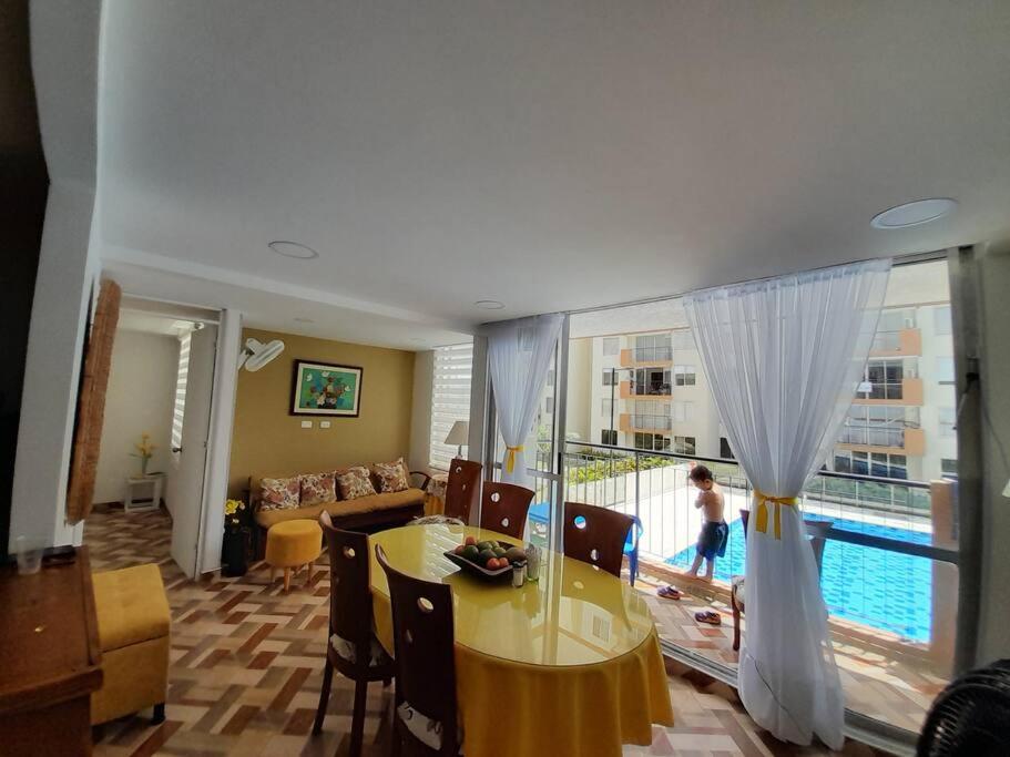 - un salon avec une table et une grande fenêtre dans l'établissement Apartamento en conjunto hacienda Peñaliza Limonar, à Ricaurte