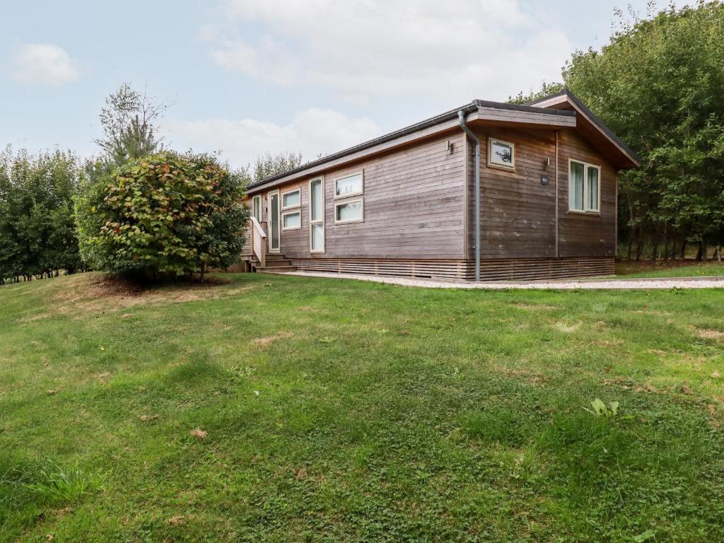 una pequeña casa de madera con un gran patio de césped en 2 Valley View, en Looe