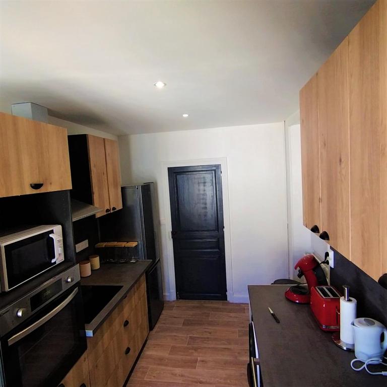 a kitchen with wooden cabinets and a black door at Halles Brauhauban Tarbes - T6 en collocation - Louez votre chambre in Tarbes