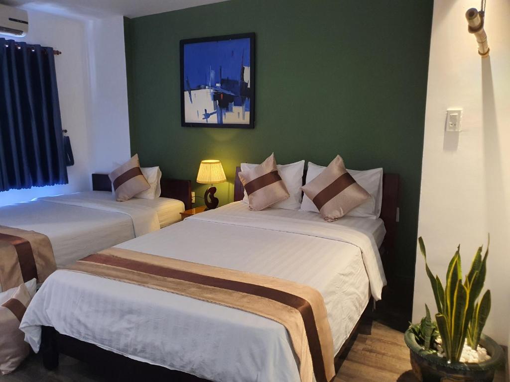 2 camas en una habitación con paredes verdes en Tony SaiGon Hotel en Ho Chi Minh