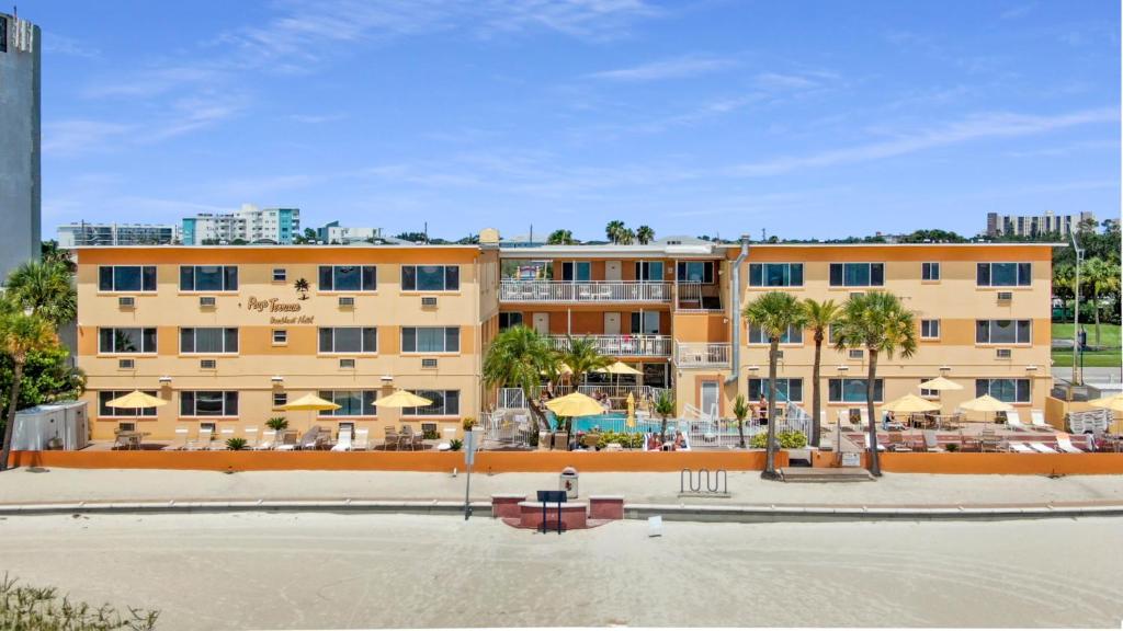 a large building with a pool and palm trees at Page Terrace Beachfront Hotel in St. Pete Beach