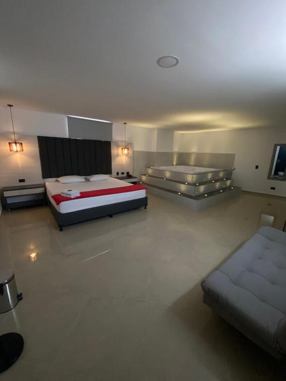 メデジンにあるHOTEL CALIFORNIA CITYのベッド2台とソファが備わる広い客室です。