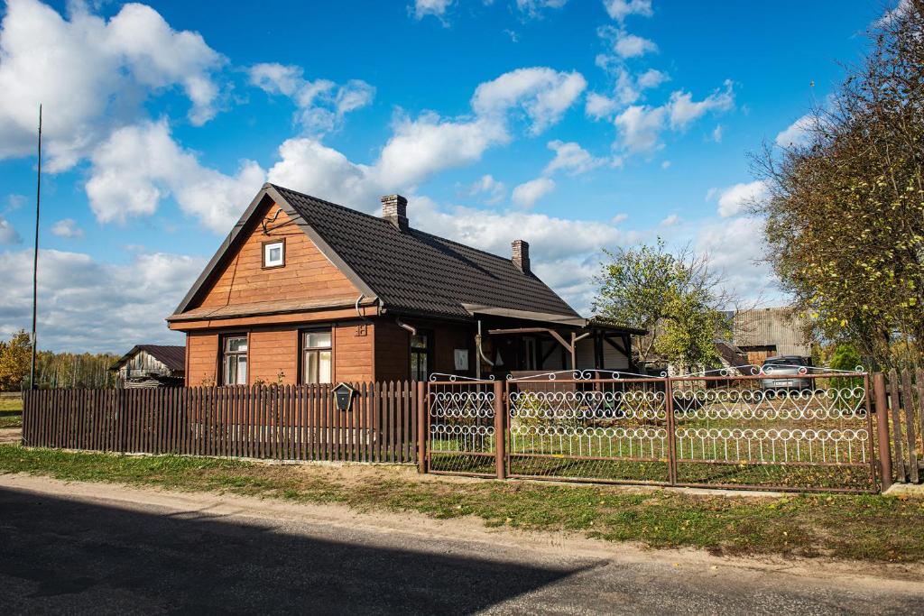 a brown house behind a fence with a wooden fence at Agroturystyka u Wojtka 