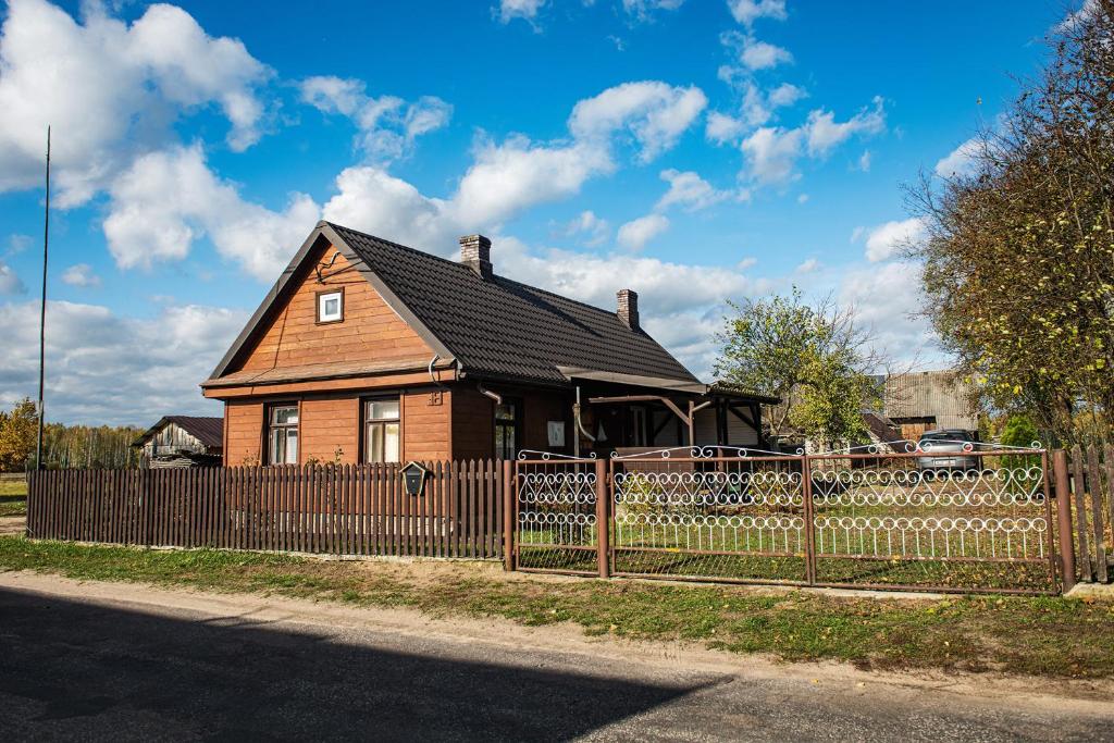 a brown house behind a fence with a wooden fence at Agroturystyka u Wojtka in Teremiski