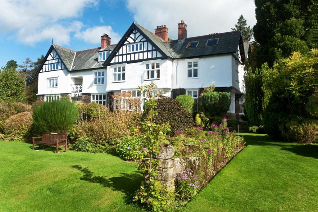 une grande maison blanche avec un jardin en face de celle-ci dans l'établissement Lindeth Howe, à Bowness-on-Windermere