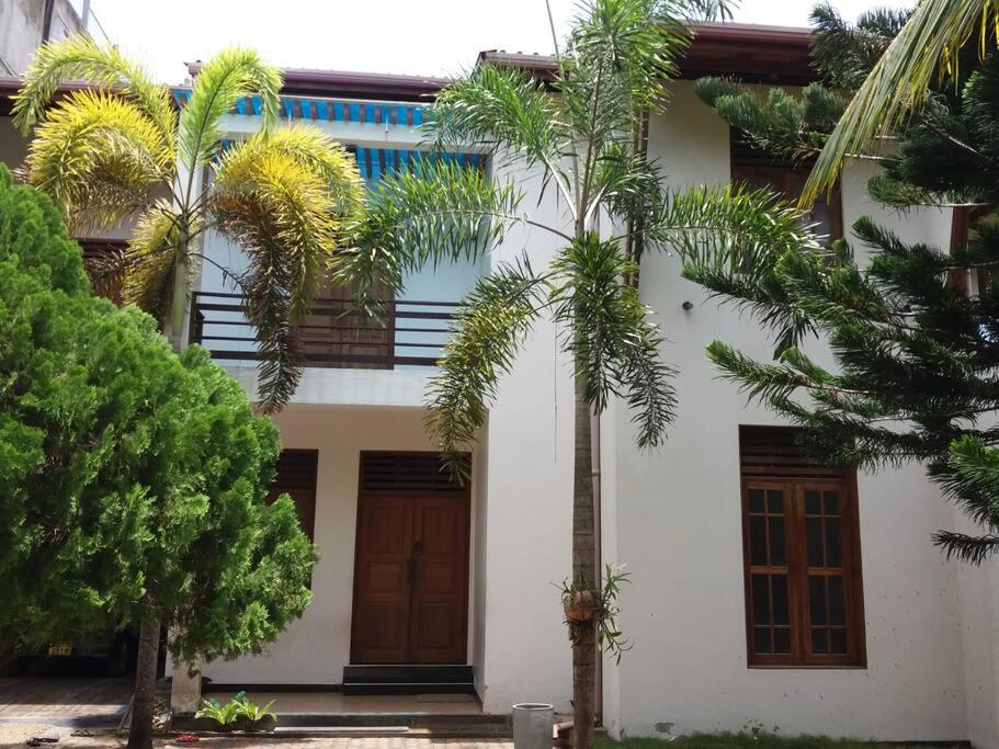 a white house with palm trees in front of it at Villa Four Seasons in Mirissa