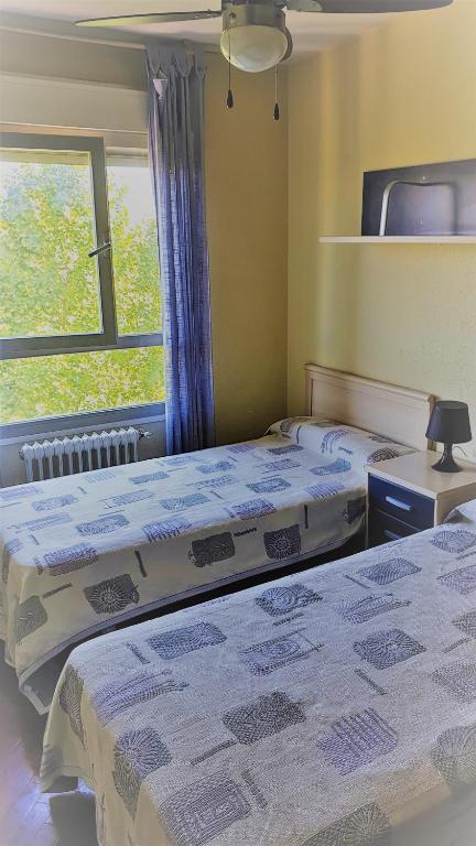 Hotel Habitación Caja Mágica, two beds in a room with a window at Habitación Caja Mágica in Madrid