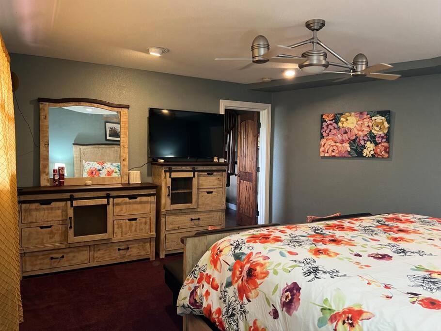 a bedroom with a bed and a dresser with a television at Entire 2br 2ba hilltop view home Sleeps 8 pets 4 acres Jacuzzi Central AC Kingbeds Free Wifi-Parking Kitchen WasherDryer Starry Terrace Two Sunset Dining Patios Grill Stovetop Oven Fridge OnsiteWoodedHiking Wildlife CoveredPatio4pets & Birds Singing! in Marble Falls