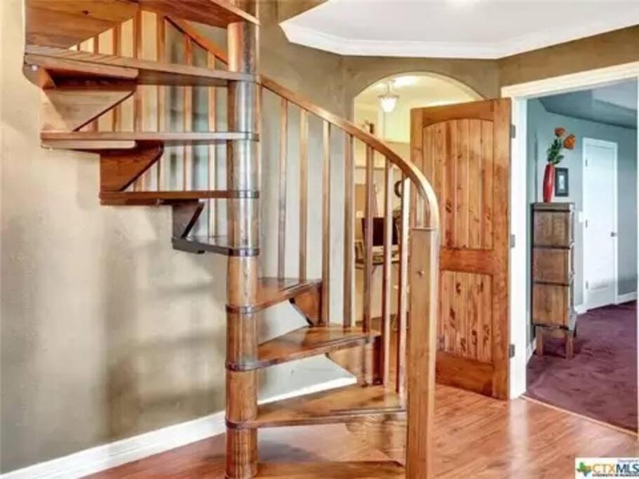 a wooden spiral staircase in a home with wooden floors at Entire 2br 2ba hilltop view home Sleeps 8 pets 4 acres Jacuzzi Central AC Kingbeds Free Wifi-Parking Kitchen WasherDryer Starry Terrace Two Sunset Dining Patios Grill Stovetop Oven Fridge OnsiteWoodedHiking Wildlife CoveredPatio4pets & Birds Singing! in Marble Falls