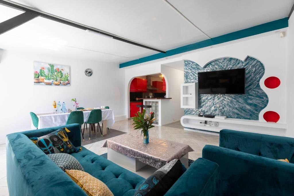 sala de estar con sofás azules y TV en Villa Comfort-Soleil, en Kourou