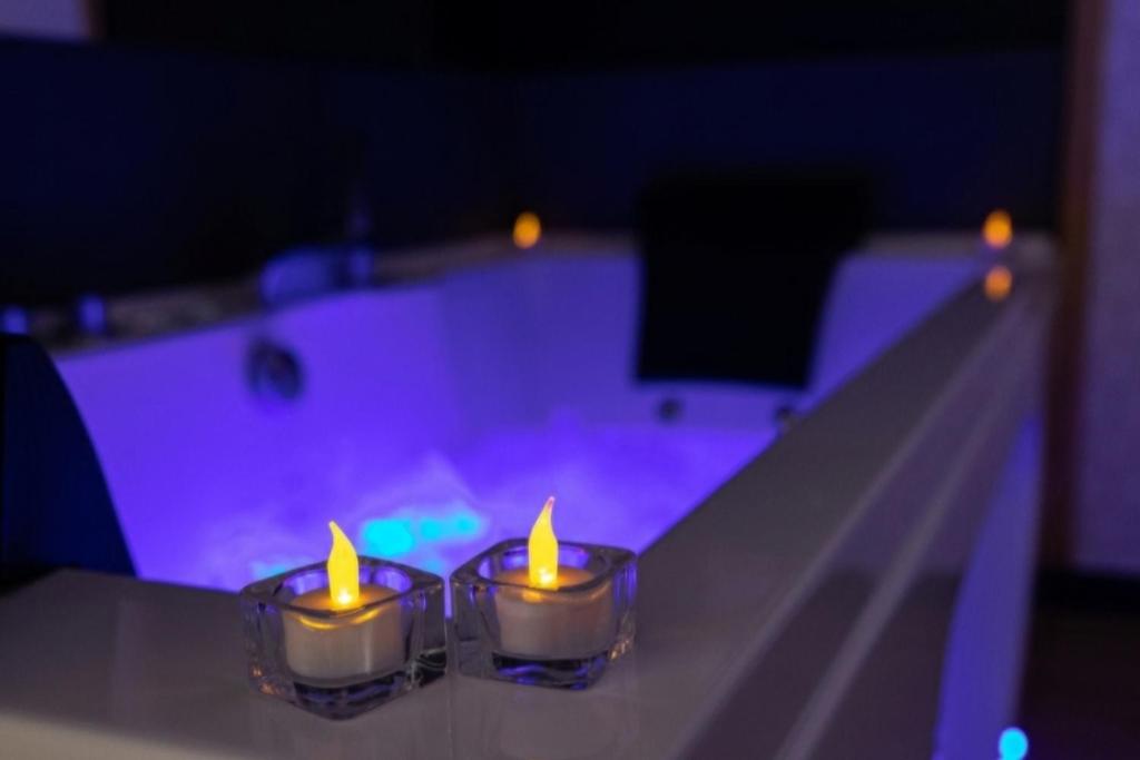 - deux bougies assises sur une table à côté d'une piscine dans l'établissement Suite romantique avec sauna et balnéo privatifs au Barcarès, au Barcarès