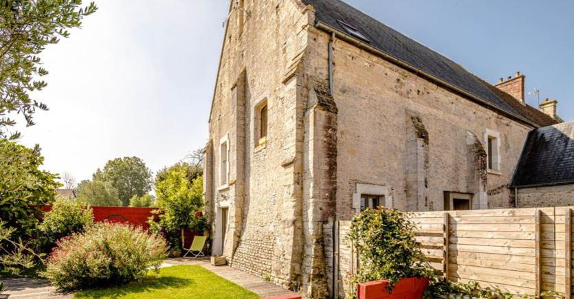 an old brick building with a fence next to it at Interludes Normands in Ver-sur-Mer