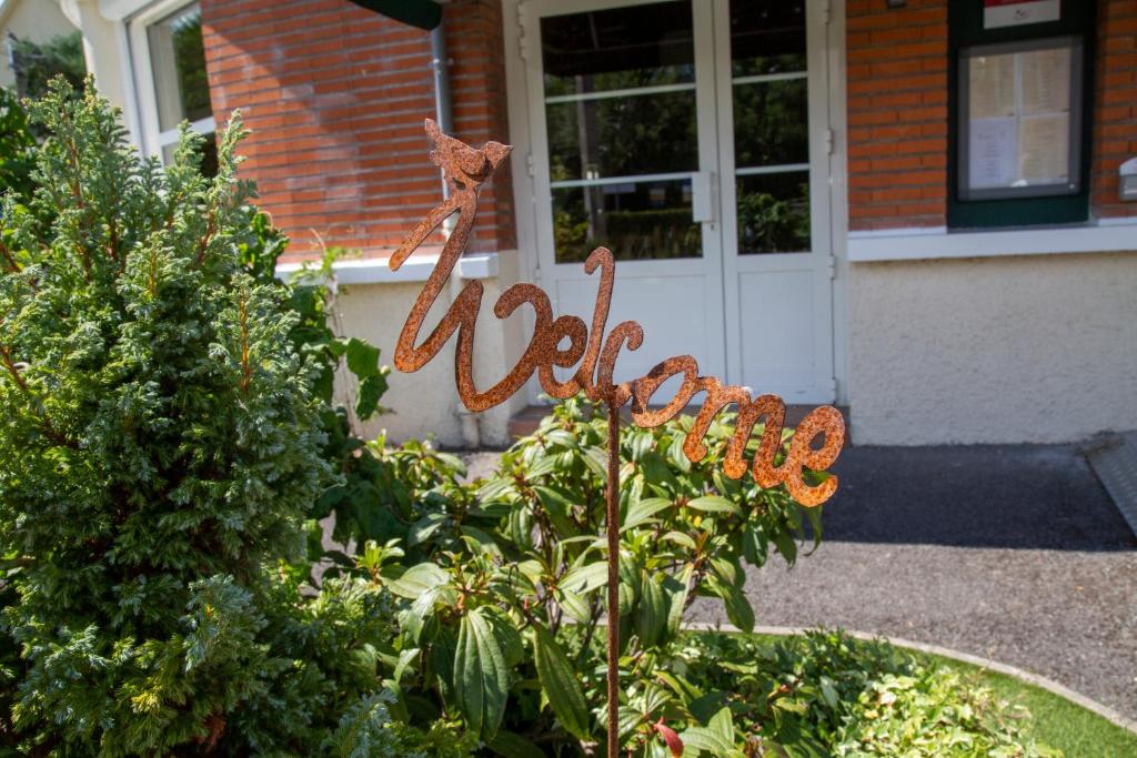 un panneau dans un jardin devant une maison dans l'établissement LOGIS - Hôtel Restaurant Du Canard, à Hangest-sur-Somme