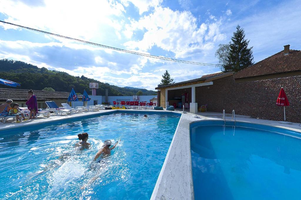 two people are playing in a swimming pool at Vila Etna in Ugrinovci