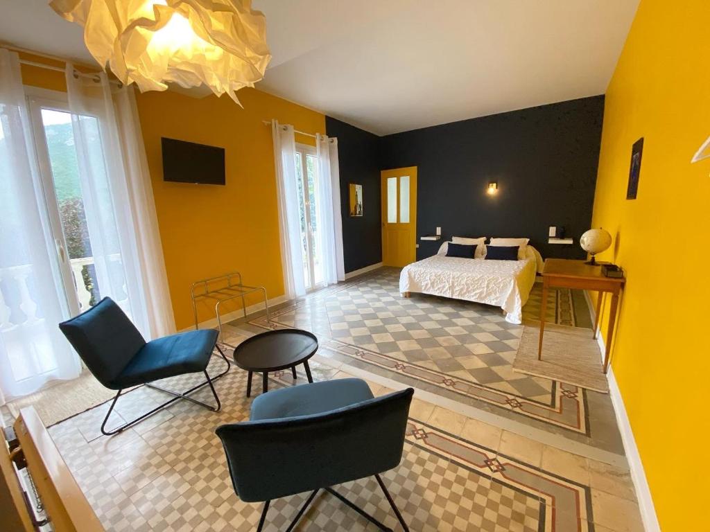 a bedroom with yellow walls and a bed and chairs at Les Terrasses in Montéglin