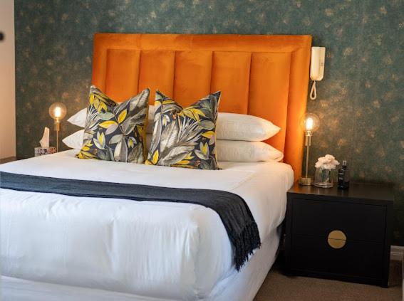 a bedroom with a bed with an orange headboard and pillows at Nal'enzo Luxe Stays in Johannesburg