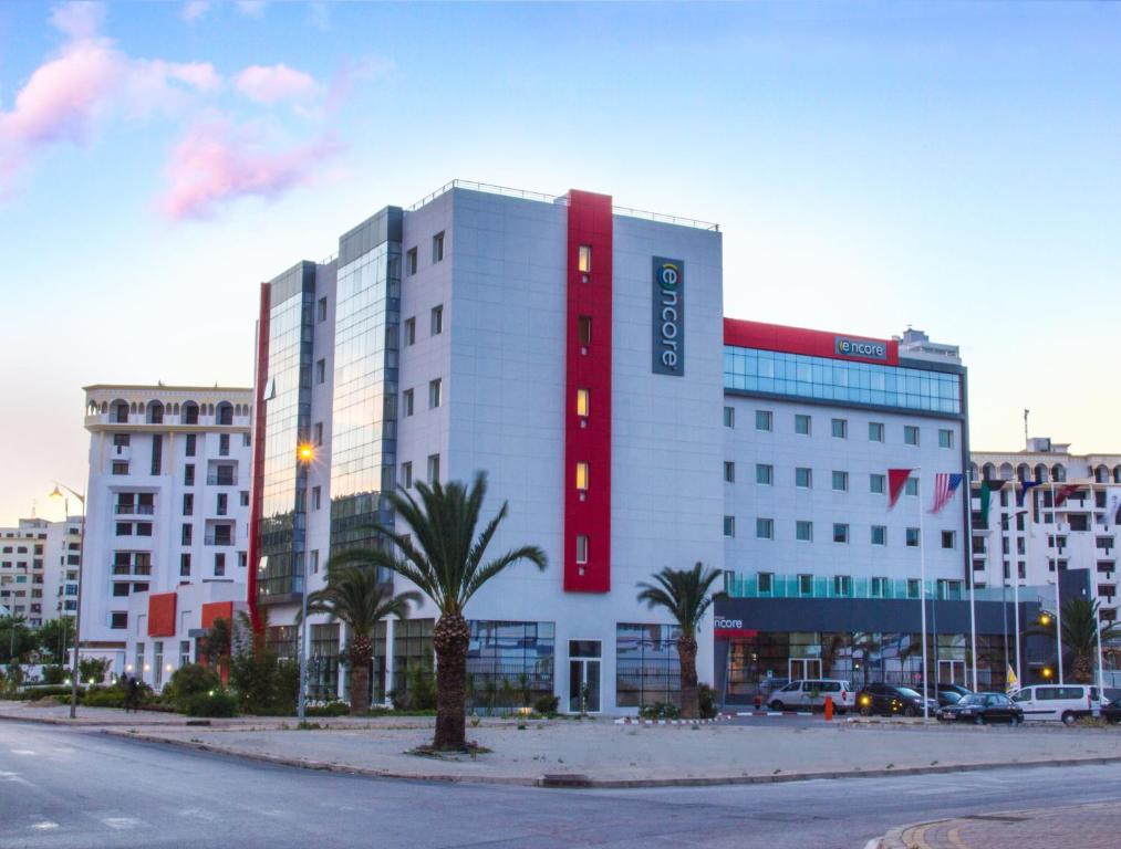 - un grand bâtiment blanc avec un panneau rouge dans l'établissement Ramada Encore By Wyndham Tangier, à Tanger