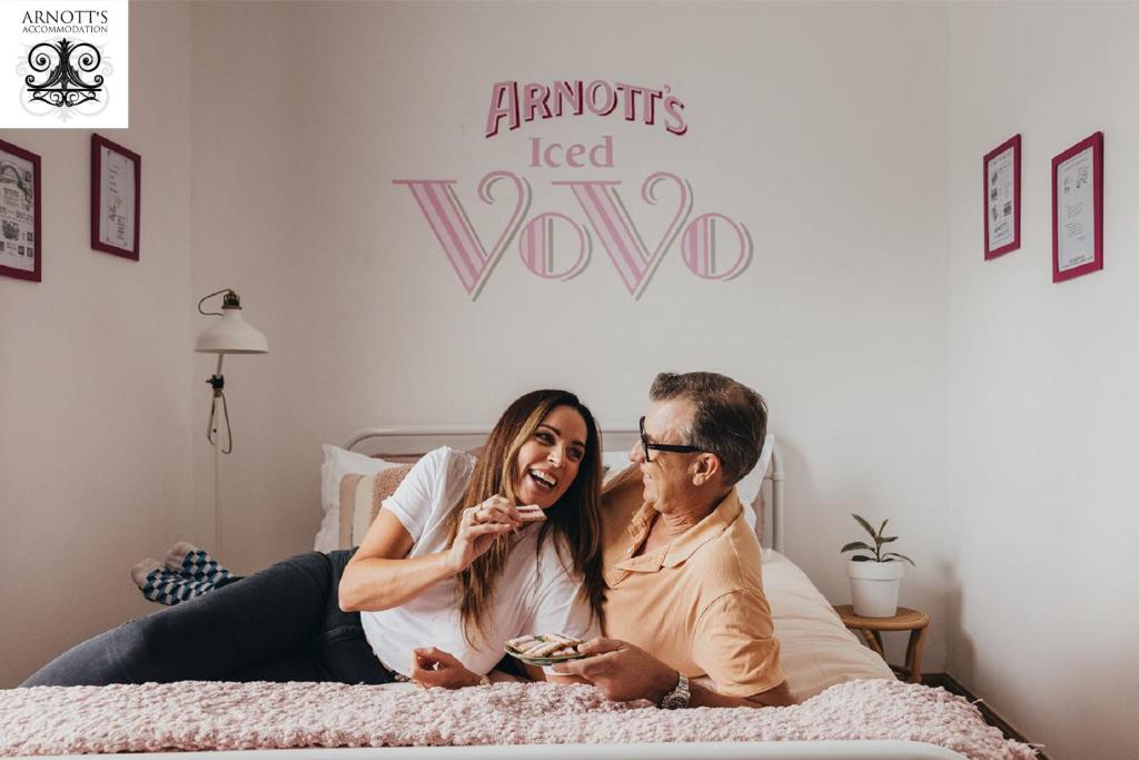 a man and a woman sitting on a bed at William Arnott Boutique Accommodation in Morpeth