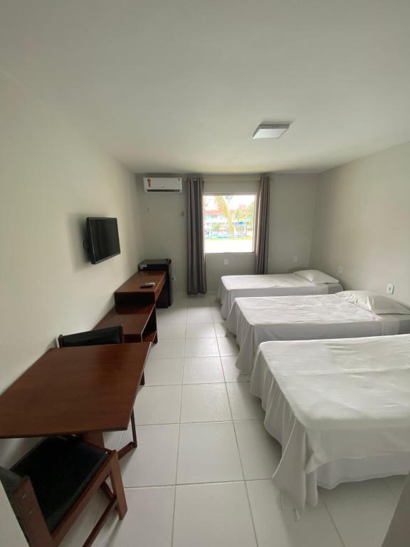 ポルト・セグロにあるQuarto139 Portobello Parkのベッド3台、デスク、テレビが備わる客室です。
