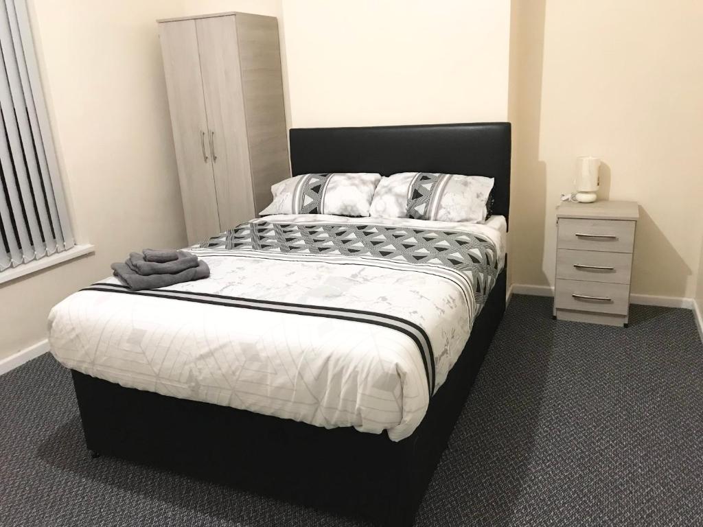 a bedroom with a large bed with white sheets and pillows at Air Host in Walsall