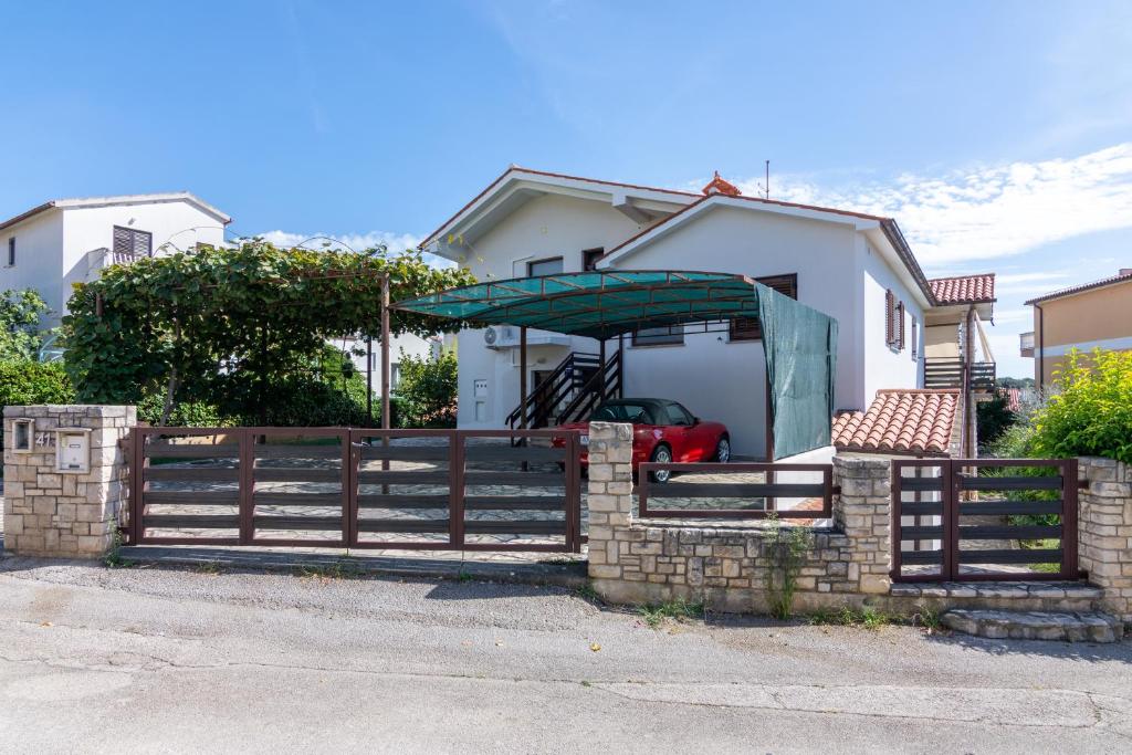 a fence in front of a house with an umbrella at Apartments with parking space Pjescana Uvala, Pula - 7349 in Pula