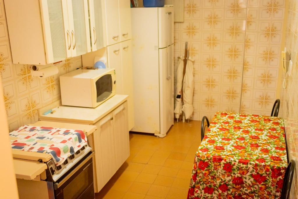 uma cozinha com um micro-ondas, uma mesa e um frigorífico em 16SOLDAPRAIA Apartamento aconchegante próximo a praia na Praia Grande