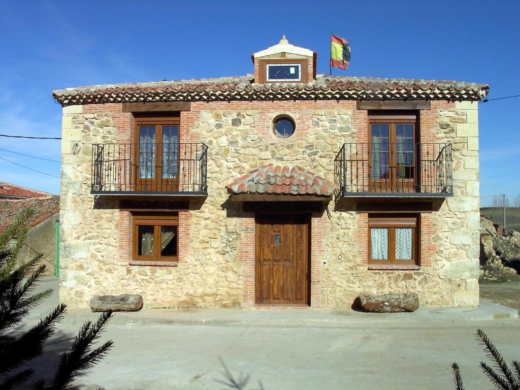 a stone house with a flag on top of it at Casa Rural Pincherres in Mata de Quintanar
