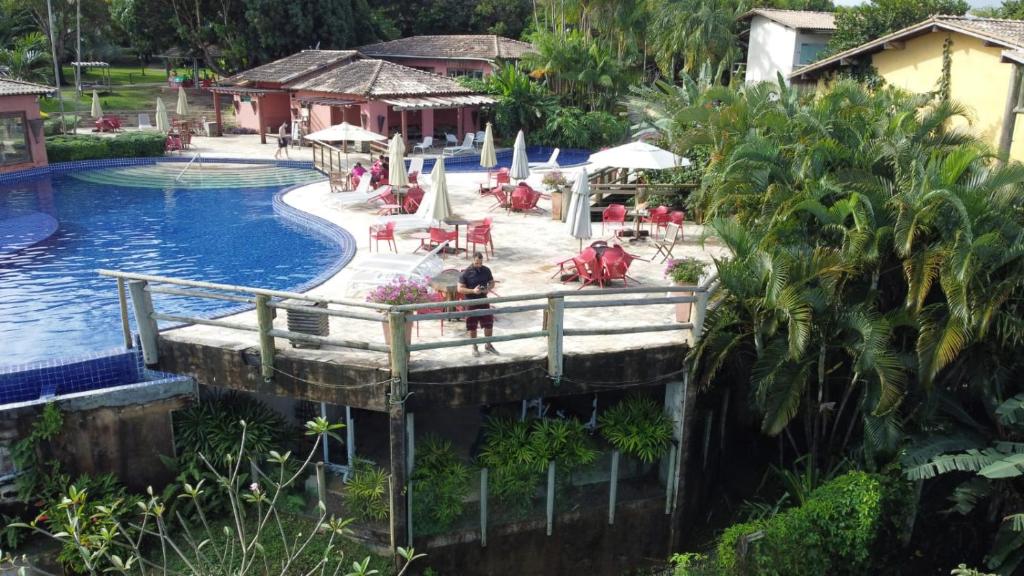 einen Pool in einem Resort mit Leuten, die auf Stühlen sitzen in der Unterkunft Villas do Pratagy Com Jacuzzy Prive Bromelia 301 in Maceió