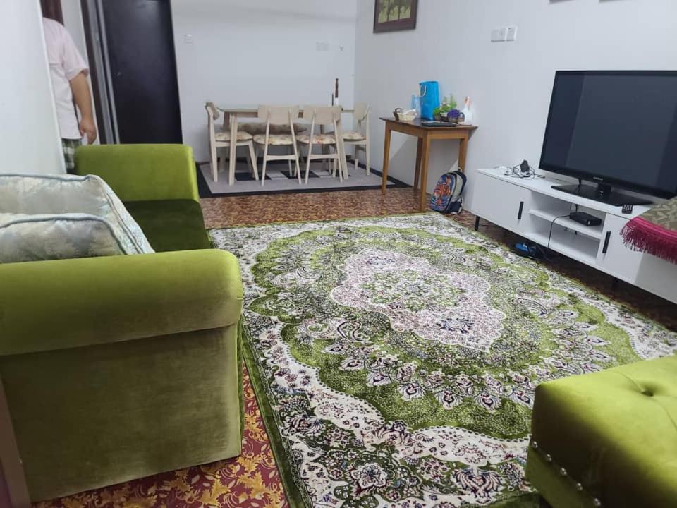 uma sala de estar com um sofá verde e um tapete em Sobey Laris Homestay KokLanas em Ketereh
