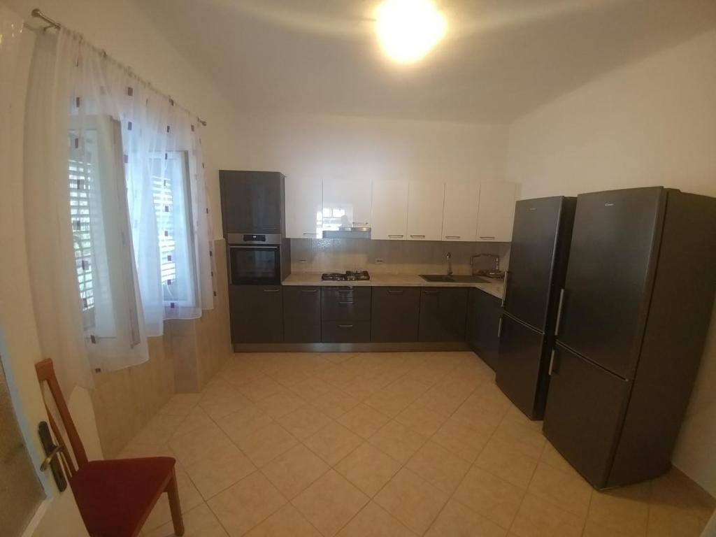 duża kuchnia z czarnymi urządzeniami i białymi szafkami w obiekcie Apartments by the sea Cove Vela Stiniva, Hvar - 19895 w mieście Zastražišće