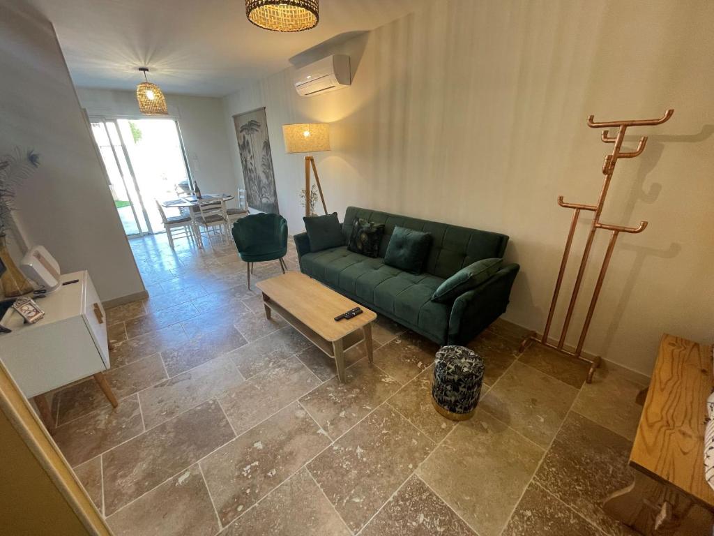 a living room with a green couch and a table at Meublé de tourisme 4 étoiles Logis Riquet proche de Carcassonne in Caux-et-Sauzens