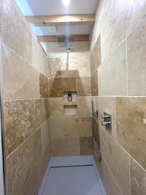 a bathroom with a shower with a stone wall at Meublé de tourisme 4 étoiles Logis Riquet proche de Carcassonne in Caux-et-Sauzens