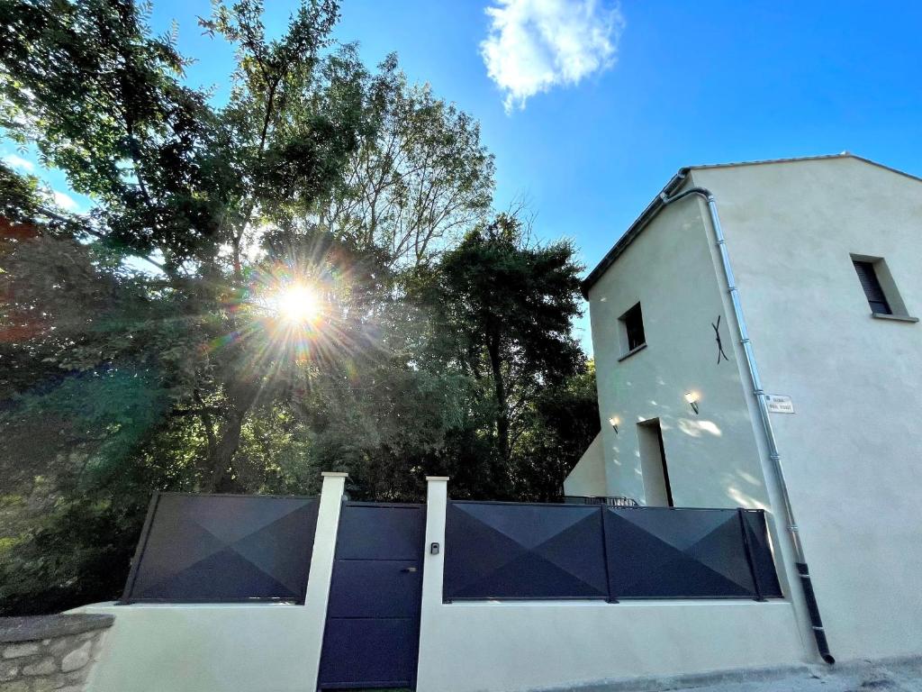 een wit huis met een poort en de zon erachter bij Meublé de tourisme 4 étoiles Logis Riquet proche de Carcassonne in Caux-et-Sauzens