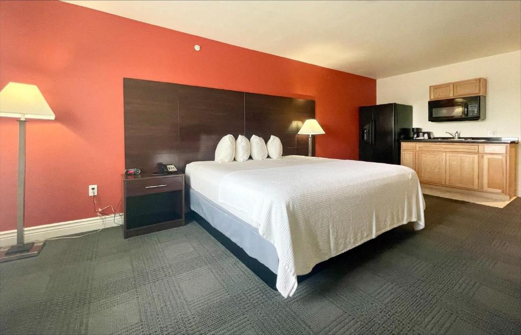 a bedroom with a large bed and a red wall at FairBridge Inn & Suites Cuero in Cuero