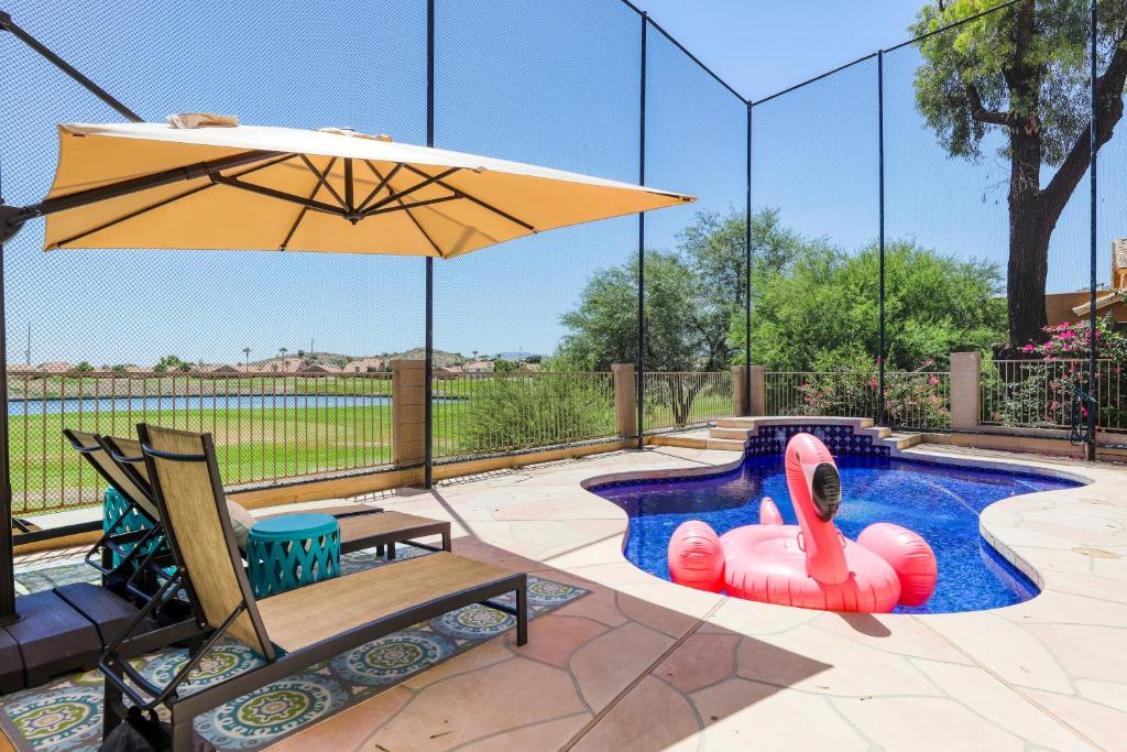 a swimming pool with an umbrella and a swan float at Luxe on the Links in Phoenix